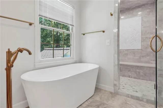a white bath tub sitting in a bathroom next to a window