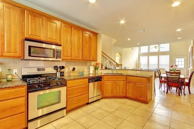 a kitchen with stainless steel appliances granite countertop wooden cabinets a stove a sink and a microwave