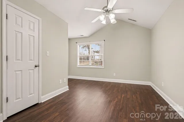 an empty room with wooden floor chandelier fan and windows