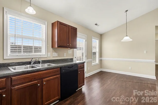 a kitchen with granite countertop a sink a window and wooden floor