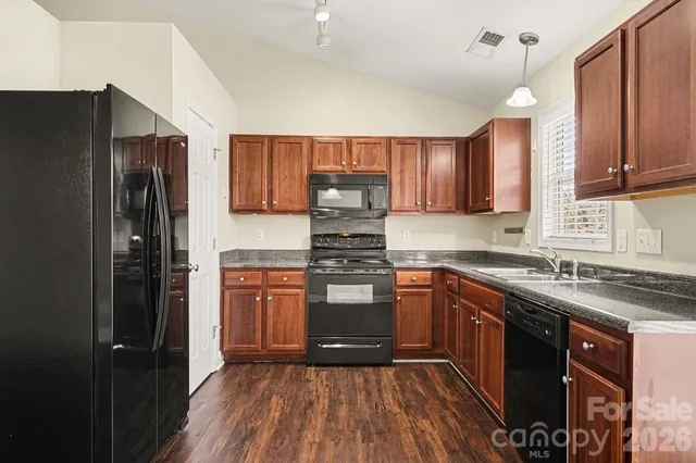 a kitchen with stainless steel appliances granite countertop wooden cabinets a stove a sink and a refrigerator