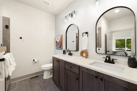 a bathroom with a double vanity sink mirror and toilet