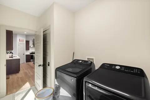 a view of an empty room and a kitchen with a stove