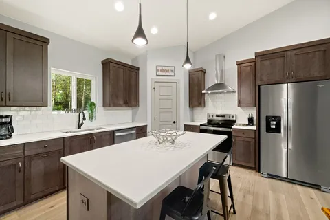 a kitchen with a refrigerator a sink a stove a dining table and chairs