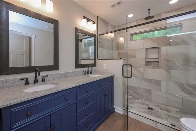 a bathroom with a shower sink vanity granite and mirror