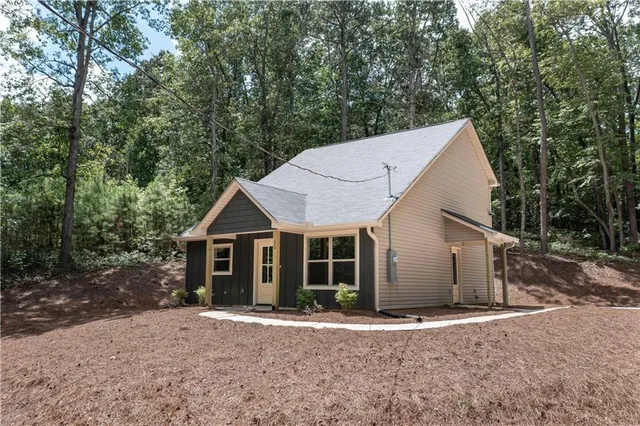 a view of a house with a yard plants and large tree