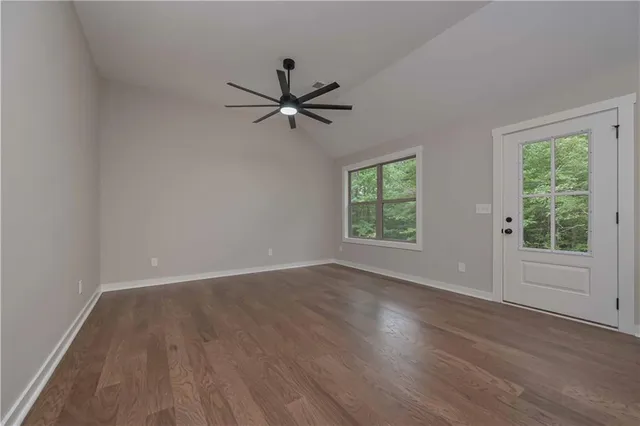 an empty room with wooden floor fan and windows