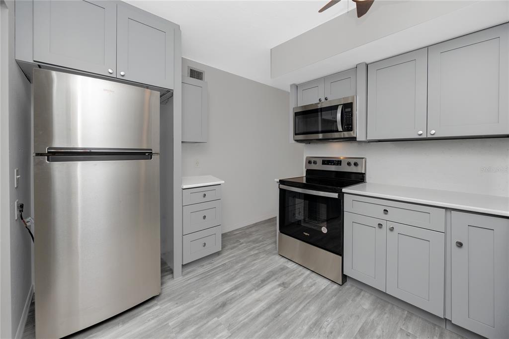 4152 55th Way North, Unit 1028 Kenneth City, FL 33709 - Photo 13 of 46 a kitchen with white cabinets and stainless steel appliances