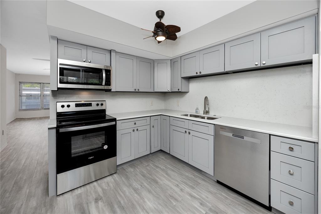 4152 55th Way North, Unit 1028 Kenneth City, FL 33709 - Photo 15 of 46 a kitchen with granite countertop a sink stainless steel appliances and cabinets