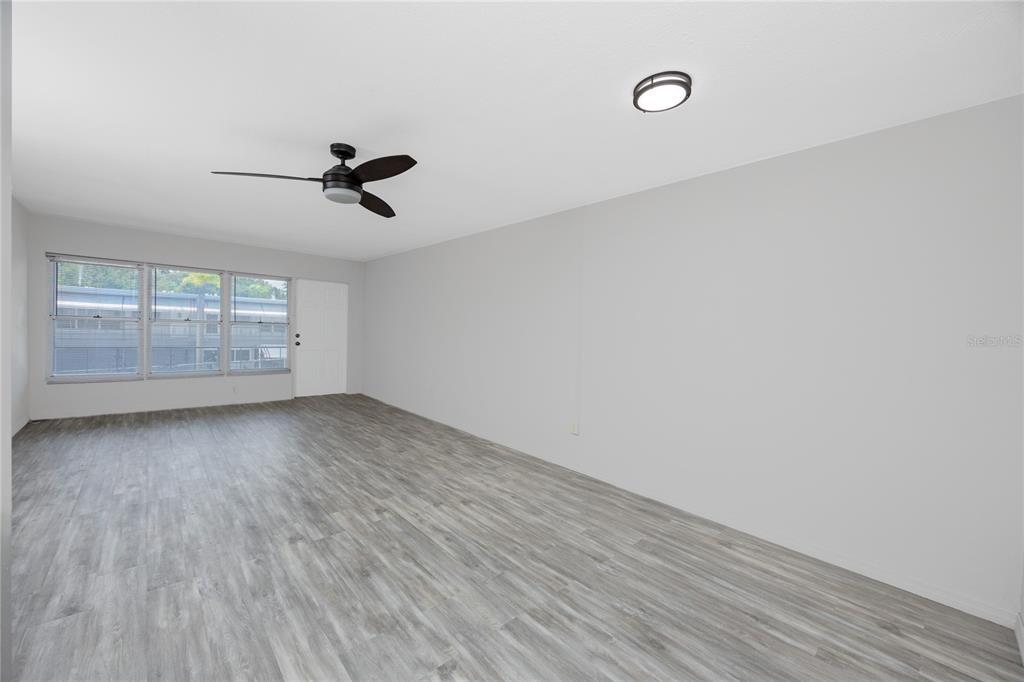 4152 55th Way North, Unit 1028 Kenneth City, FL 33709 - Photo 9 of 46 a view of an empty room with wooden floor and a window