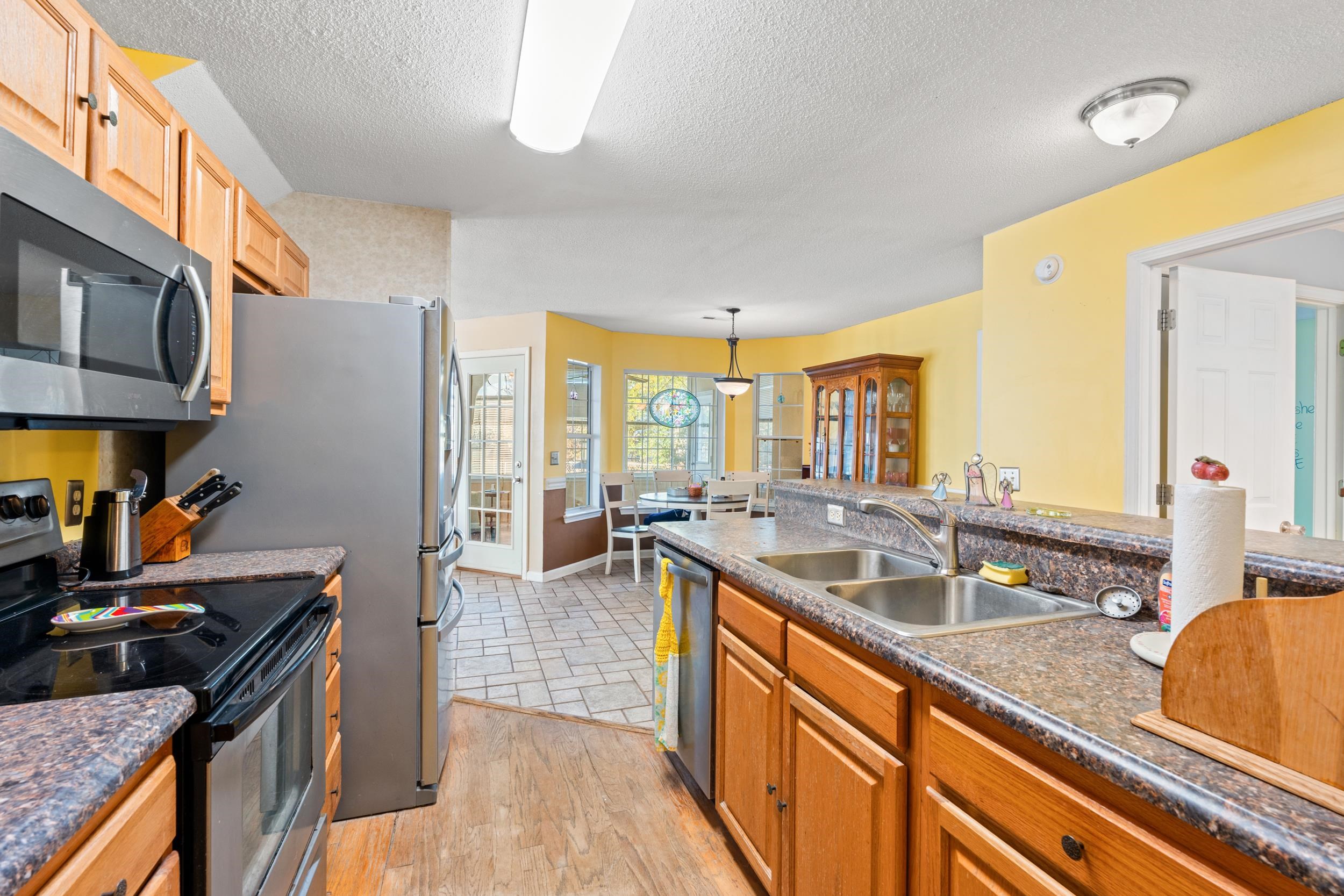 539 Drake Lane Surfside Beach, SC 29575 - Photo 7 of 38 Kitchen with appliances with stainless steel finishes, hanging light fixtures, a textured ceiling, light wood finished floors, and brown cabinetry