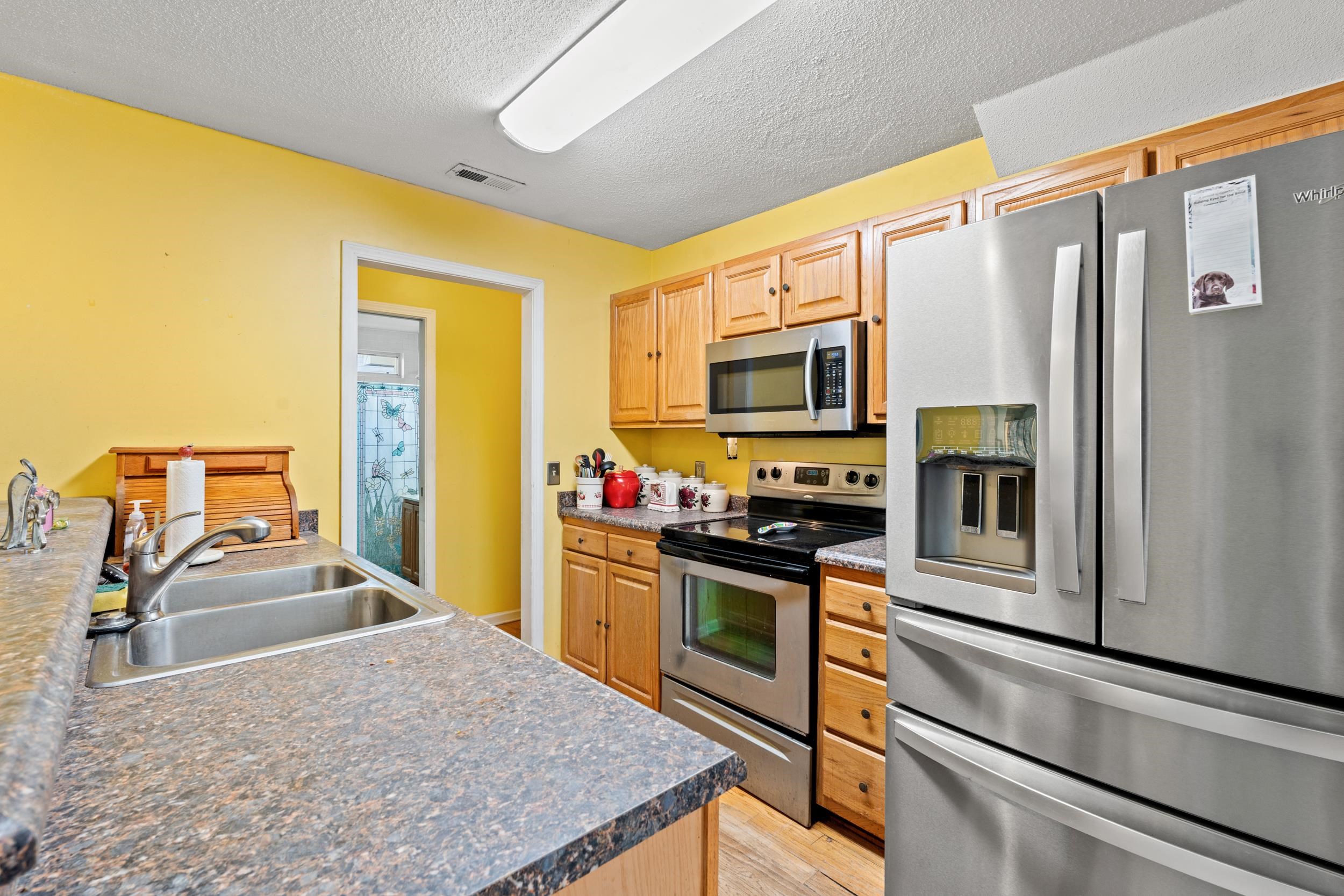 539 Drake Lane Surfside Beach, SC 29575 - Photo 8 of 38 Kitchen with appliances with stainless steel finishes, a textured ceiling, dark countertops, and light wood-style flooring