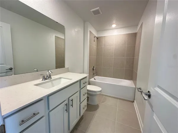 a bathroom with a granite countertop sink toilet mirror and bathtub