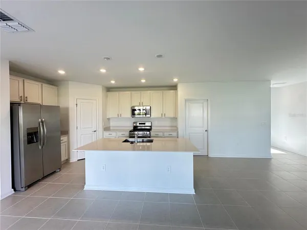 a large kitchen with stainless steel appliances a large counter top and a refrigerator