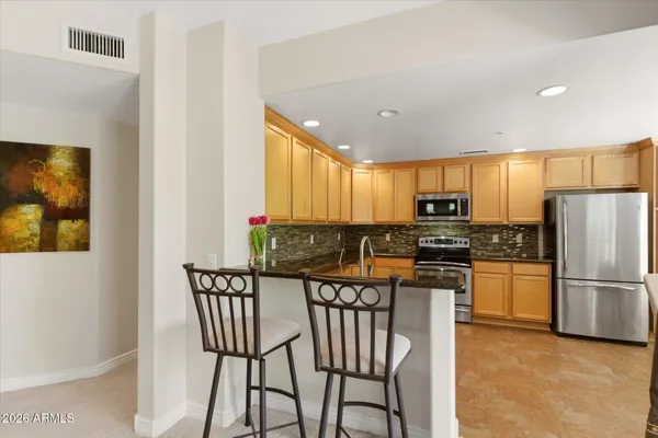 a kitchen with stainless steel appliances kitchen island granite countertop a refrigerator a stove a microwave oven with a dining table and chairs