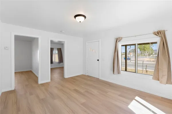 a view of an empty room with wooden floor and a window