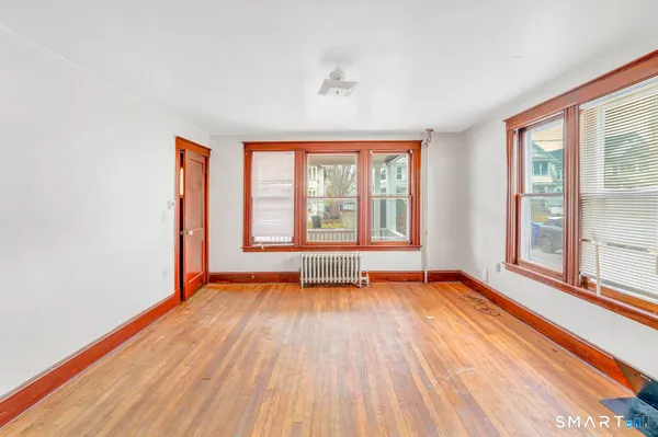 a view of an empty room with wooden floor and a window