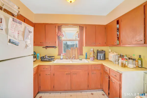 a kitchen with a refrigerator a stove a sink dishwasher and wooden cabinets with wooden floor