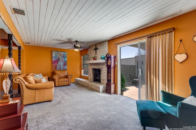 a living room with furniture a ceiling fan and a large window
