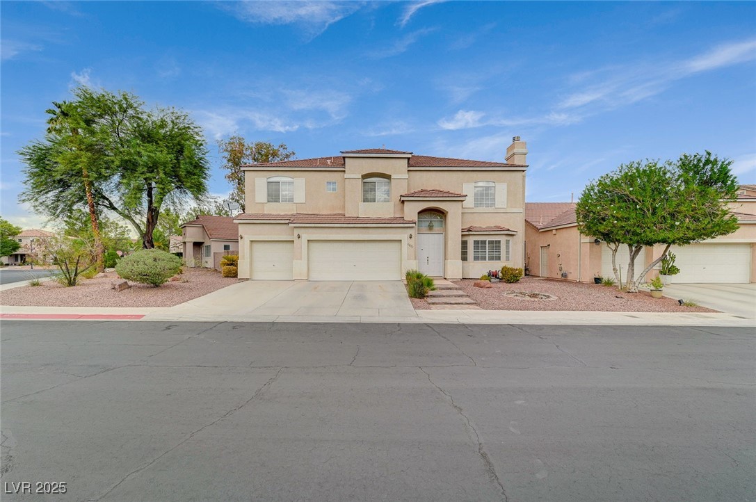 Mediterranean / spanish-style home with driveway, a garage, a chimney, and stucco siding