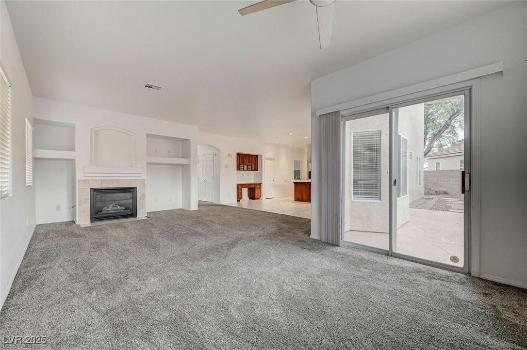 6012 Prospector Trail Las Vegas, NV 89118 - Photo 12 of 73 Unfurnished living room featuring a fireplace, carpet, ceiling fan, built in features, and arched walkways