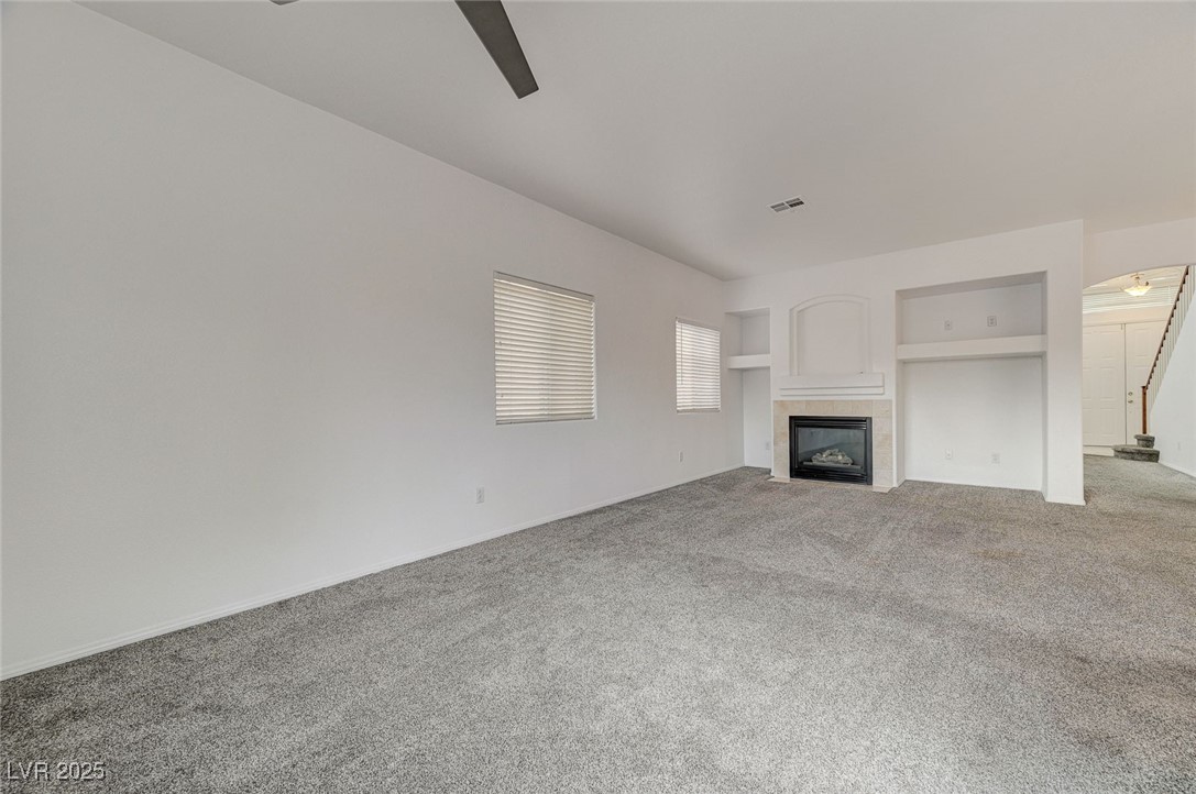 6012 Prospector Trail Las Vegas, NV 89118 - Photo 13 of 73 Unfurnished living room with ceiling fan, a tile fireplace, and carpet flooring
