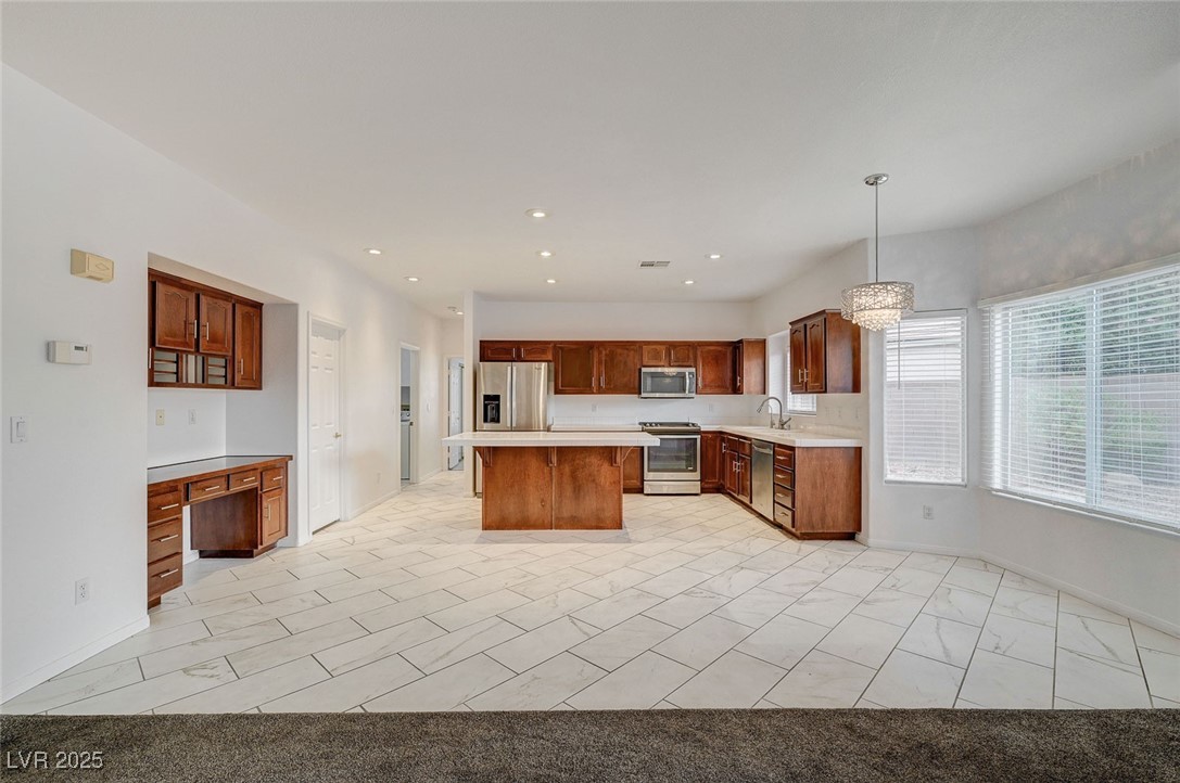 6012 Prospector Trail Las Vegas, NV 89118 - Photo 16 of 73 Kitchen featuring light countertops, appliances with stainless steel finishes, built in desk, a kitchen bar, and a center island
