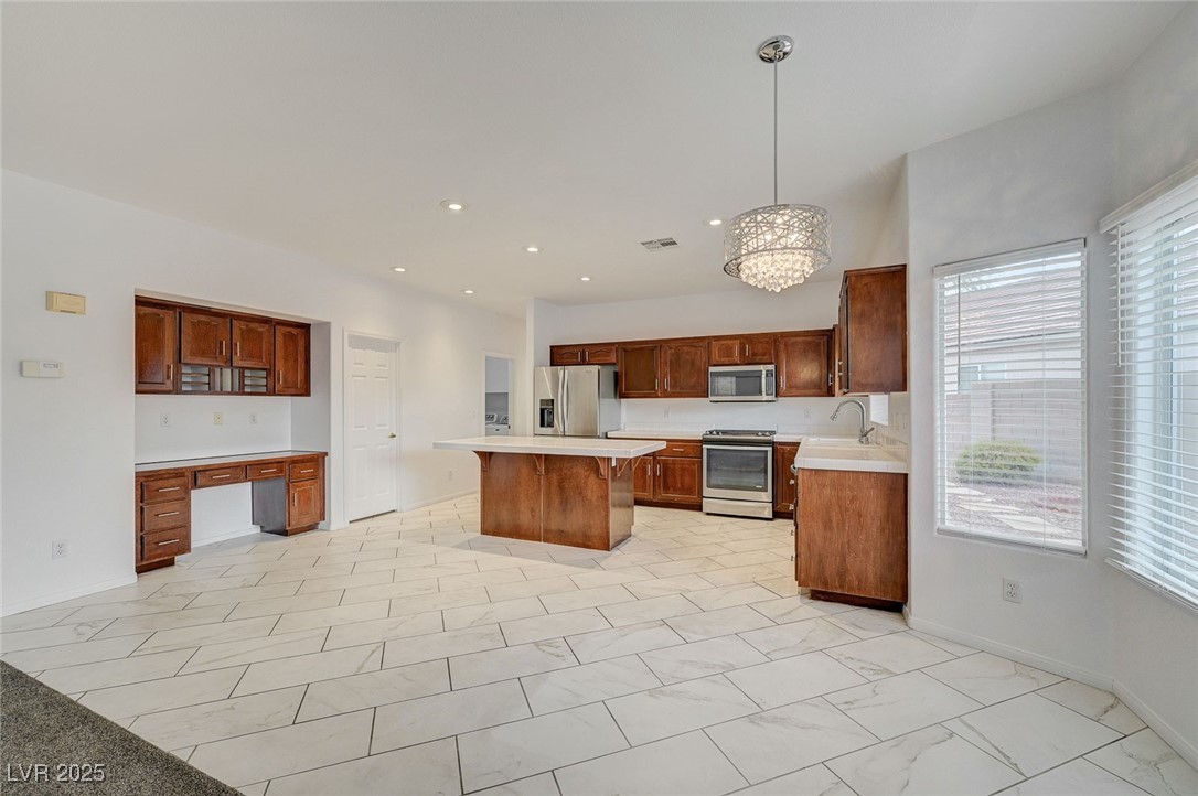 6012 Prospector Trail Las Vegas, NV 89118 - Photo 17 of 73 Kitchen featuring appliances with stainless steel finishes, light countertops, pendant lighting, built in desk, and a chandelier