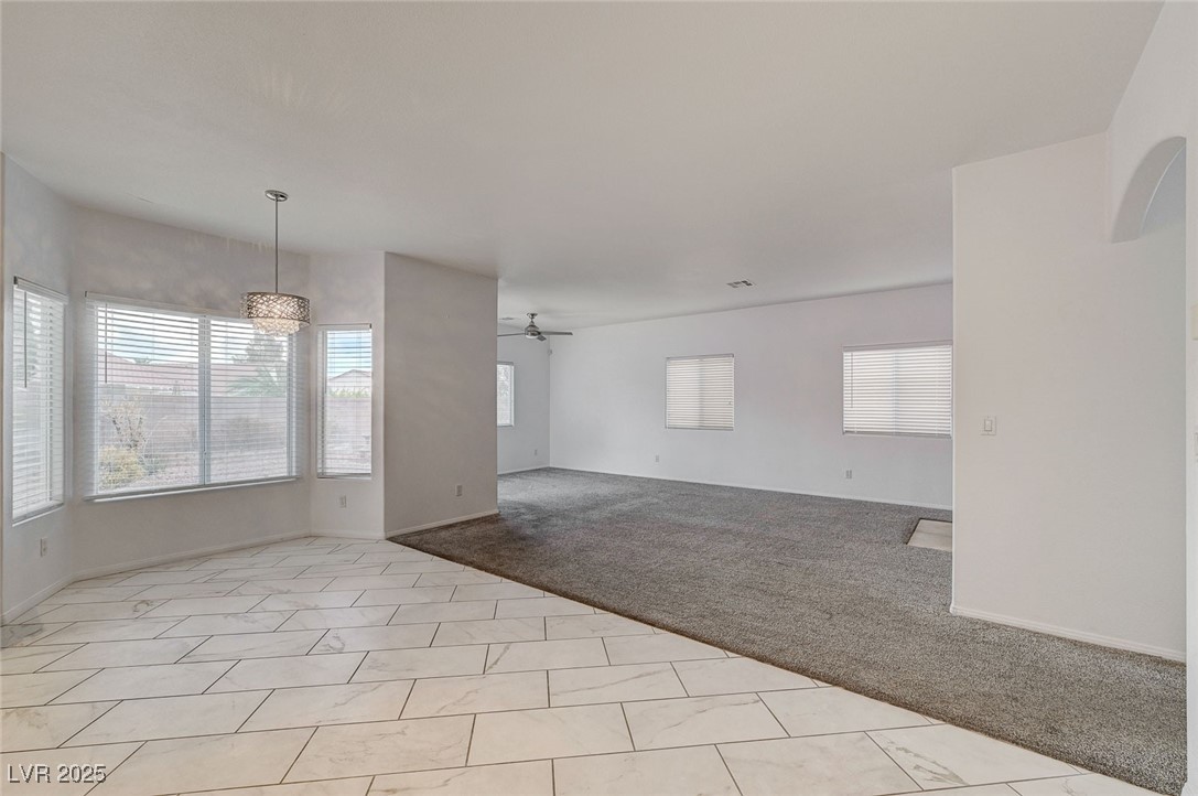 6012 Prospector Trail Las Vegas, NV 89118 - Photo 18 of 73 Unfurnished living room with light carpet, light tile patterned floors, a ceiling fan, and healthy amount of natural light
