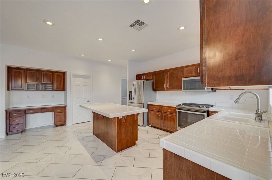 6012 Prospector Trail Las Vegas, NV 89118 - Photo 20 of 73 Kitchen with tile counters, appliances with stainless steel finishes, a center island, recessed lighting, and a breakfast bar