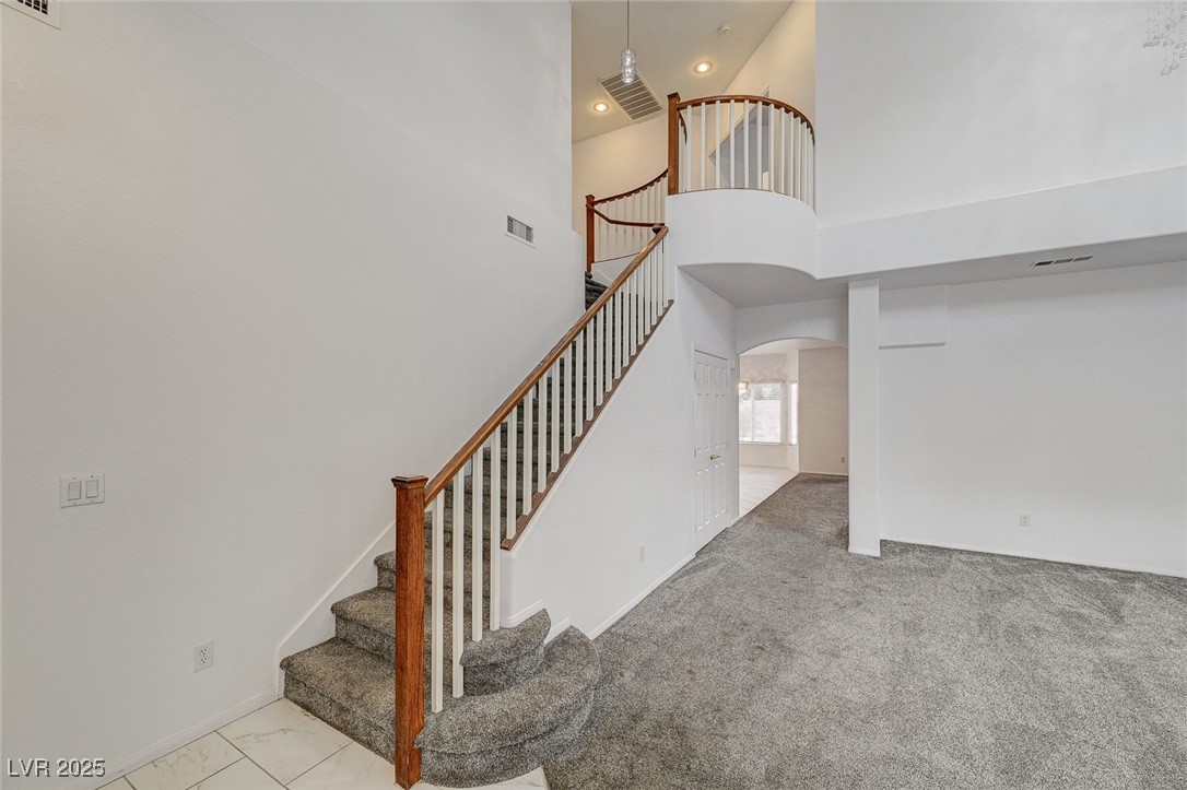 6012 Prospector Trail Las Vegas, NV 89118 - Photo 31 of 73 Staircase with a towering ceiling, arched walkways, and carpet floors