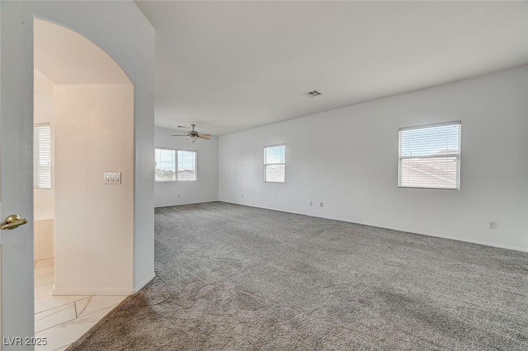 6012 Prospector Trail Las Vegas, NV 89118 - Photo 36 of 73 Empty room with light colored carpet, arched walkways, and a ceiling fan