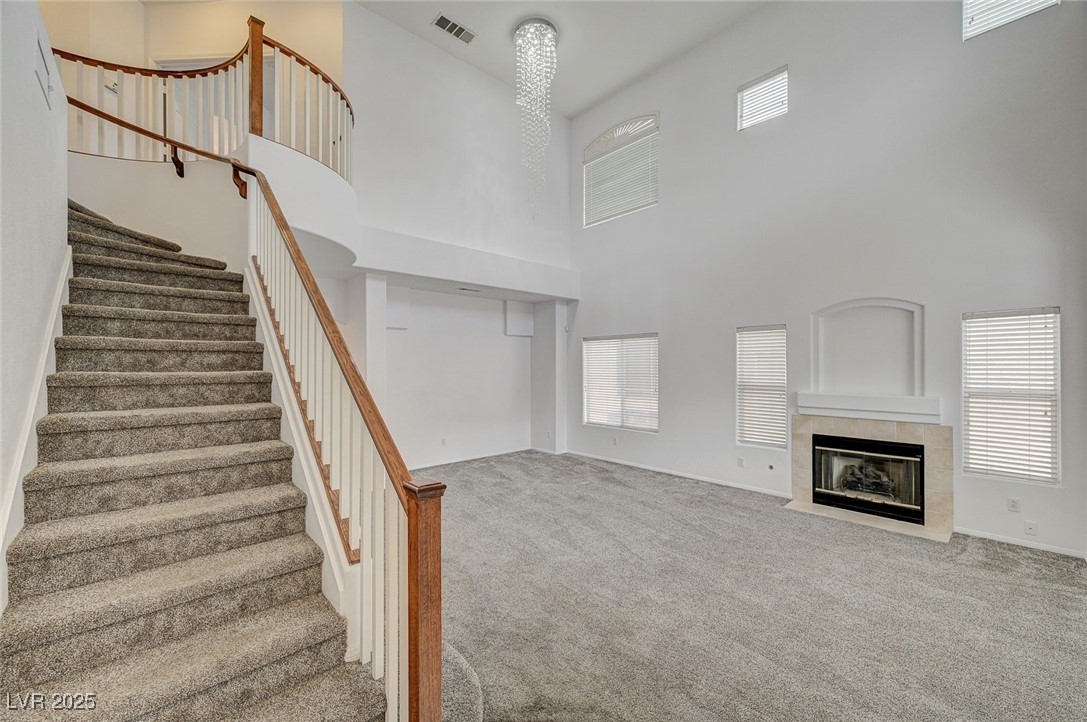 6012 Prospector Trail Las Vegas, NV 89118 - Photo 6 of 73 Unfurnished living room featuring carpet flooring, a towering ceiling, a fireplace, and stairs