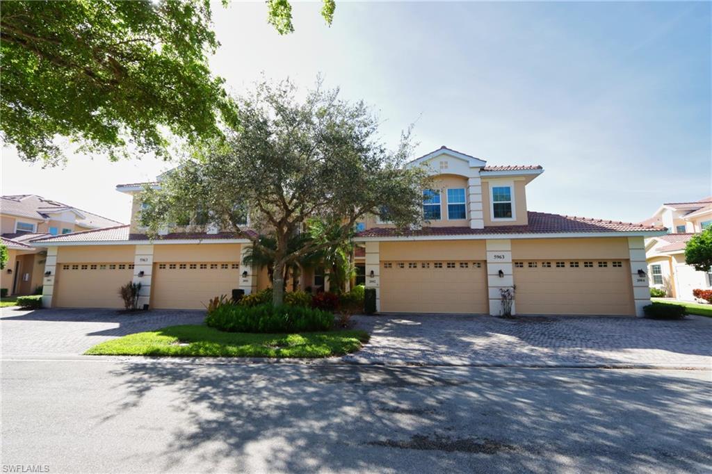 5963 Trophy Drive, Unit 2002 Naples, FL 34110 - Photo 24 of 33 a large house with a large parking space and a car parked in front of it