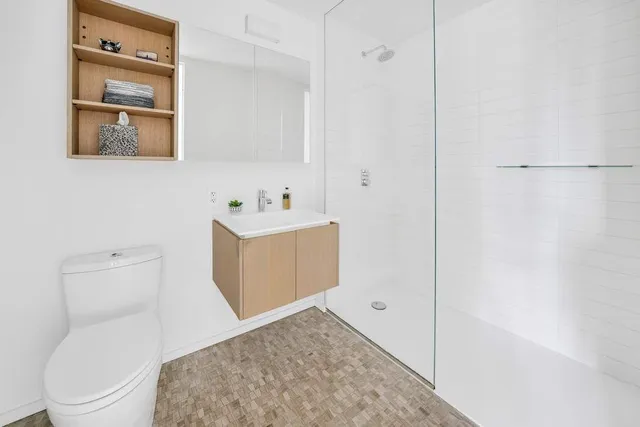 a large bedroom with a bed and large mirror with wooden floor