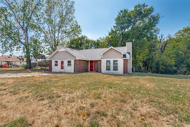 a front view of a house with yard and large trees