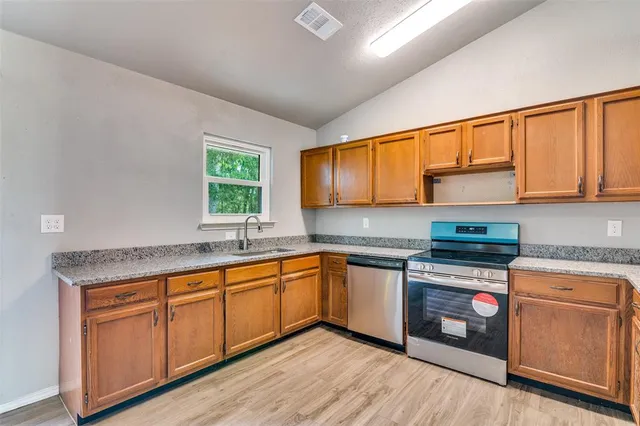 a kitchen with stainless steel appliances granite countertop wooden cabinets a sink and dishwasher with wooden floor