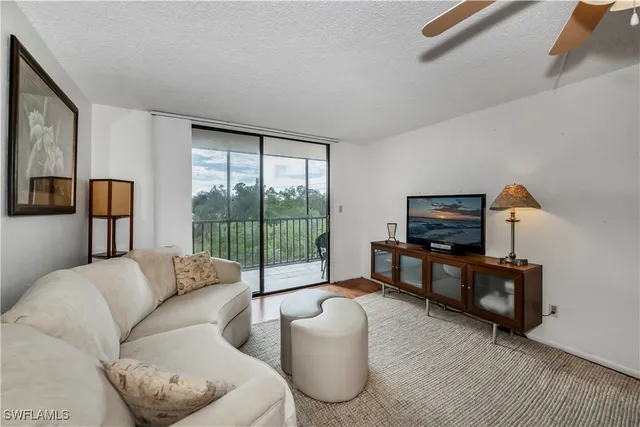 a living room with furniture a flat screen tv and floor to ceiling window