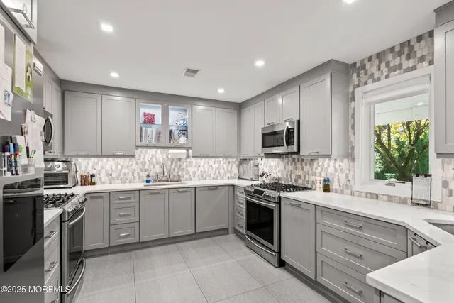 a kitchen with granite countertop a sink stainless steel appliances and white cabinets