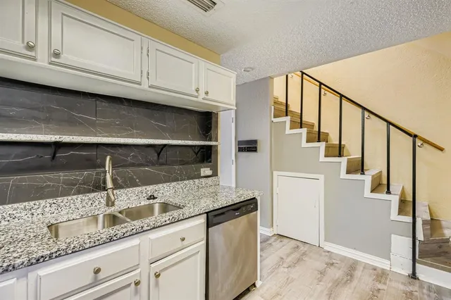 a kitchen with granite countertop a sink a stove and cabinets