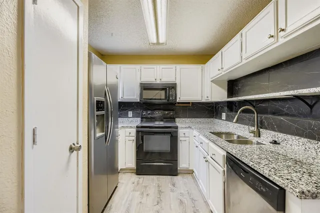 a kitchen with granite countertop a sink stainless steel appliances and cabinets