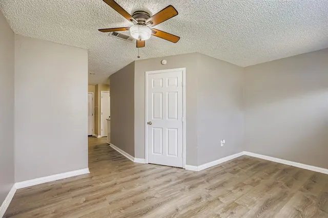 wooden floor in an empty room with a chandelier fan