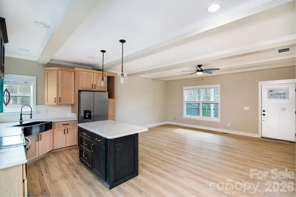 a large room with kitchen island wooden floor and stainless steel appliances