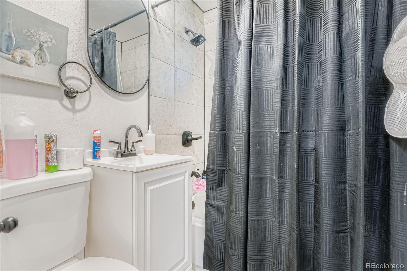 8805 West 46th Avenue Wheat Ridge, CO 80033 - Photo 19 of 25 a bathroom with a sink a toilet and shower curtain
