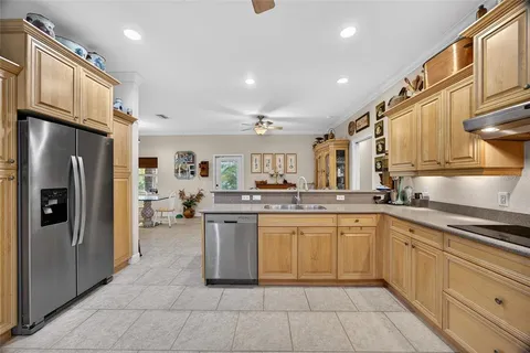 a kitchen with stainless steel appliances kitchen island granite countertop a refrigerator a stove top oven and a sink with wooden floor