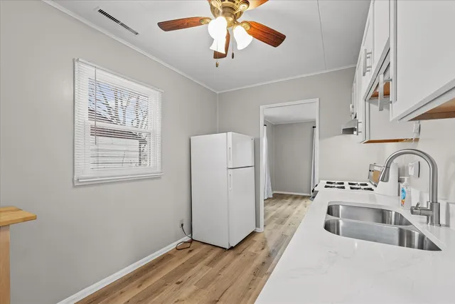a kitchen with stainless steel appliances a white counter top a sink and a window