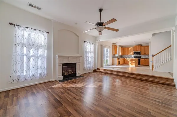 a view of a livingroom with wooden floor a fireplace a ceiling fan and window