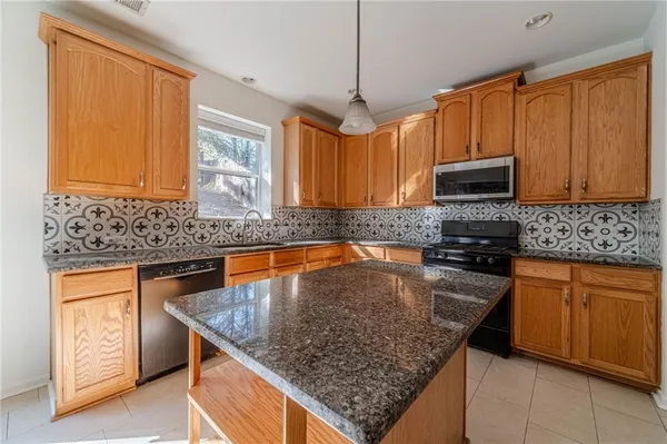 a kitchen with stainless steel appliances granite countertop a sink a counter space and cabinets