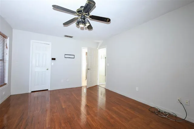 an empty room with wooden floor fan and windows