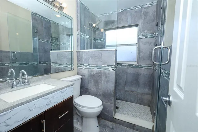 a bathroom with a granite countertop sink toilet and shower